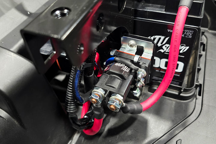 UTV Stereo relay mounted near a 12V battery with red power cables connected