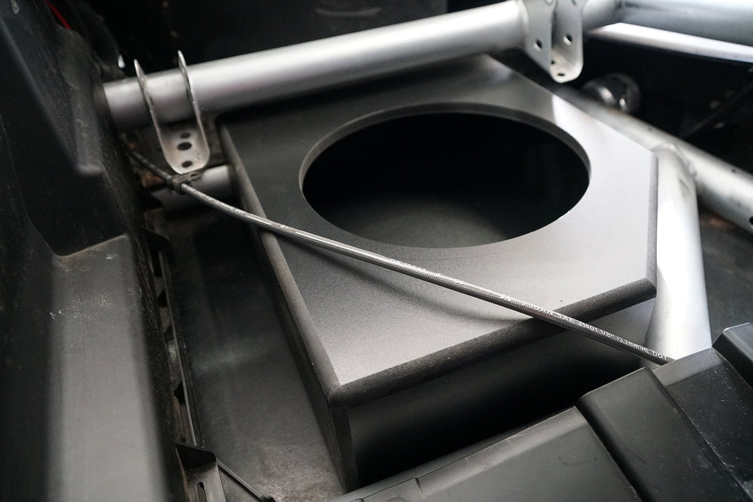 Black subwoofer enclosure box mounted in a vehicle frame