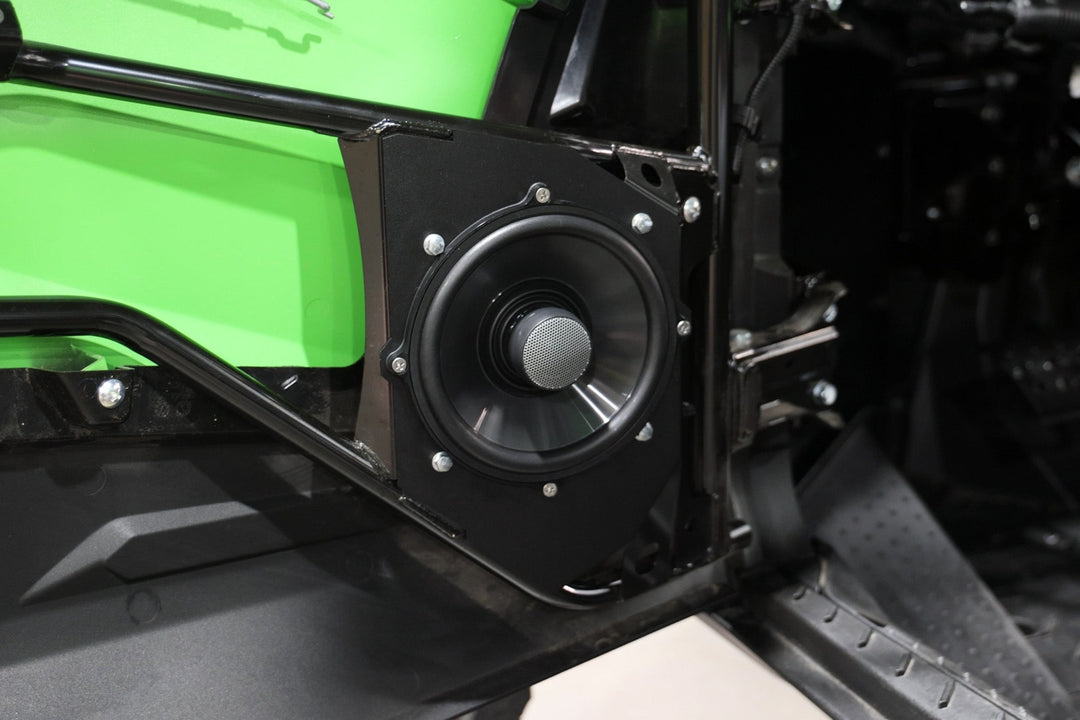 Black audio speaker mounted on a green vehicle door frame