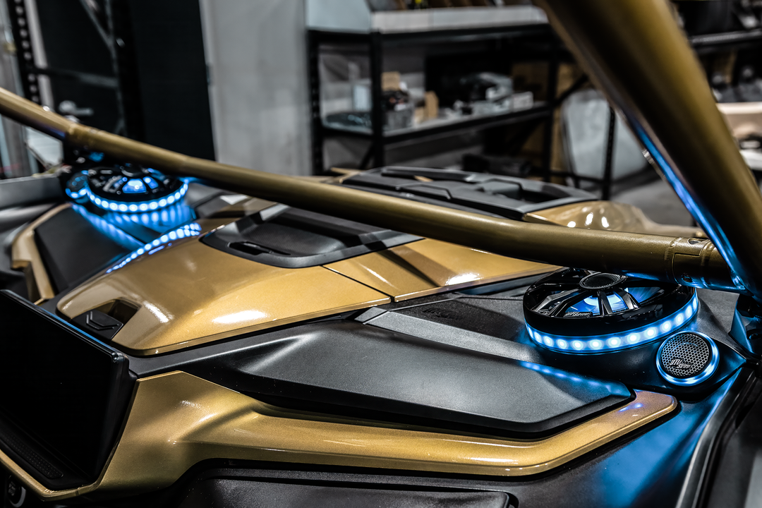 UTV Stereo speakers with blue LED rings installed in a gold off-road vehicle dashboard