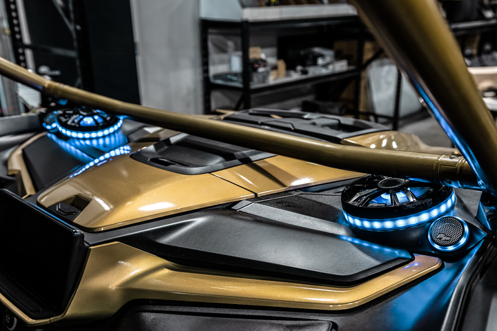UTV Stereo speakers with blue LED rings installed in a gold off-road vehicle dashboard