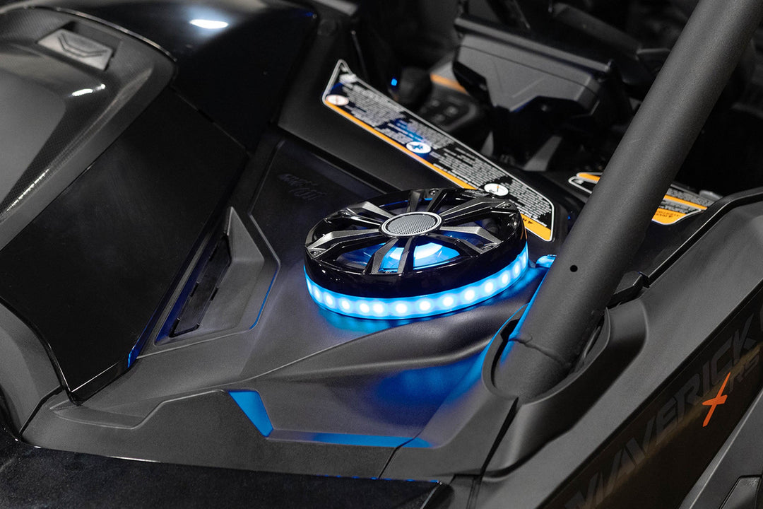 Round black speaker with blue LED ring light mounted on vehicle dashboard
